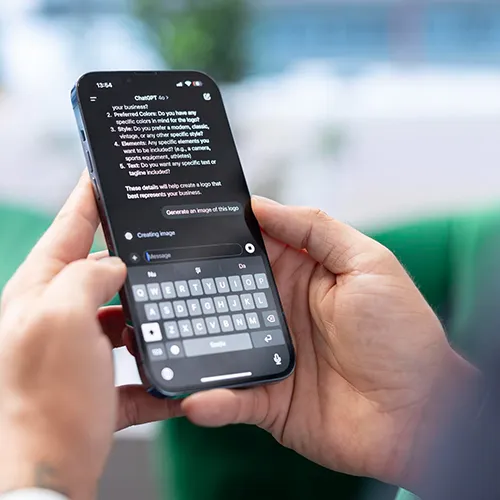 Zwei Hände, die ein Smartphone halten, auf dem ChatGPT auf dem Bildschirm zu sehen ist.